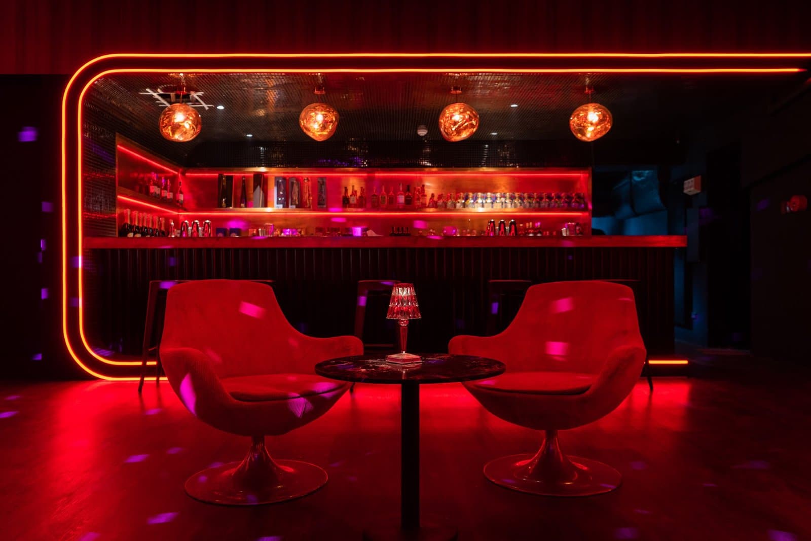 Bar shelves and a pink neon sign.